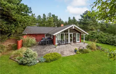 a small red house with a patio in a yard at Three-Bedroom Holiday Home In Hurup Thy in Sindrup