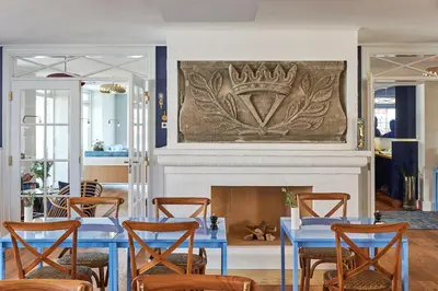 a dining room with blue tables and a fireplace at Strandhotellet in Blokhus
