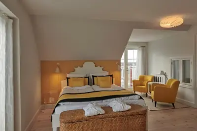 a bedroom with a large bed and two chairs at Strandhotellet in Blokhus