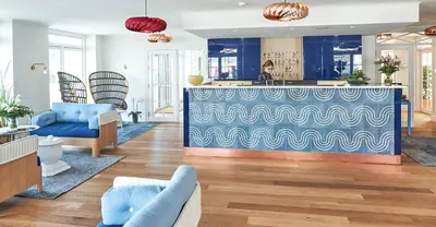 a lobby with a blue counter and a man in the background at Strandhotellet in Blokhus