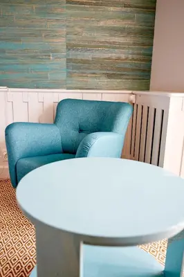 a living room with a blue couch and two tables at Strandhotellet in Blokhus