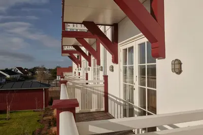 a white house with red and white railing at Strandhotellet in Blokhus