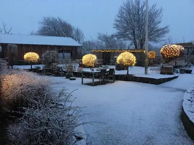 a yard covered in snow with a table and lights at B & B Langagergaard in Thisted