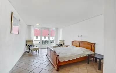 a bedroom with a bed and two chairs in it at Bakkegården in Thisted