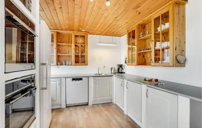 a kitchen with white cabinets and a wooden ceiling at Bakkegården in Thisted