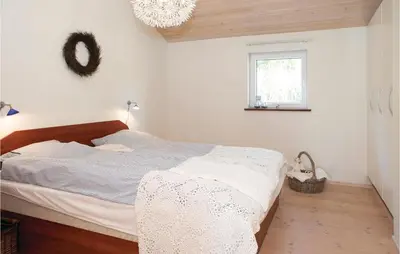 a bedroom with a bed and a window and a chandelier at Three-Bedroom Holiday Home In Blokhus in Blokhus
