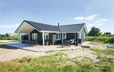 a small house with chairs and tables on a beach at Four-Bedroom Holiday Home In Vestervig in Vestervig