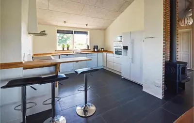 a kitchen with a stove and some stools in it at Four-Bedroom Holiday Home In Vestervig in Vestervig