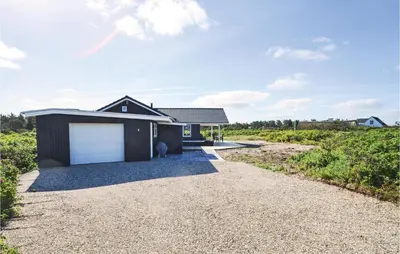 a house with a garage on a gravel driveway at Four-Bedroom Holiday Home In Vestervig in Vestervig