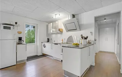 a kitchen with white cabinets and a wooden floor at Four-Bedroom Holiday Home In Spottrup in Spottrup