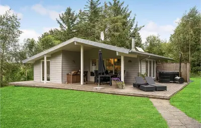 a small white house with a deck in a yard at Four-Bedroom Holiday Home In Spottrup in Spottrup