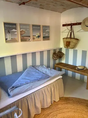 a bedroom with a bed and a shelf on the wall at Porshus Ferielejlighed in Sundstrup