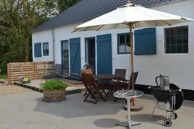 a patio with a table and chairs and an umbrella at Porshus Ferielejlighed in Sundstrup
