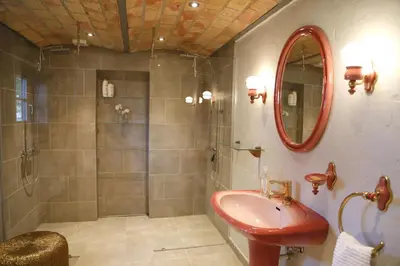 a bathroom with a shower and a sink and a mirror at Porshus Ferielejlighed in Sundstrup