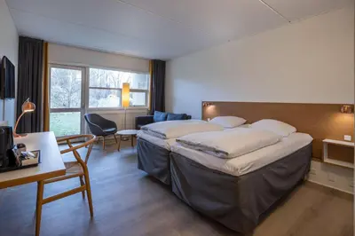 a hotel room with two beds and a desk and chair at Comwell Rebild Bakker in Skorping