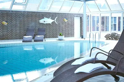 a swimming pool with two chairs and a fish on the wall at Montra Hotel Hanstholm in Hanstholm