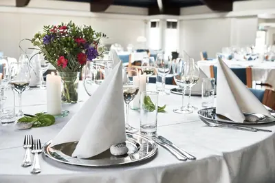 a table with white napkins and silver plates on it at Montra Hotel Hanstholm in Hanstholm