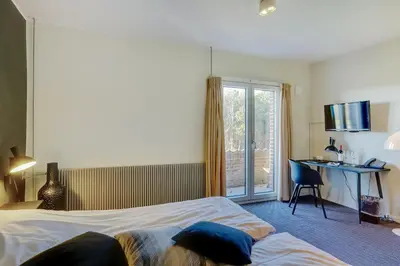 a hotel room with two beds and a desk and a window at Montra Hotel Hanstholm in Hanstholm