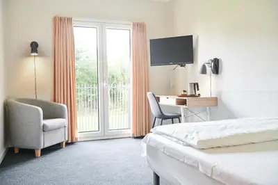 a hotel room with a bed and a desk and a window at Montra Hotel Hanstholm in Hanstholm
