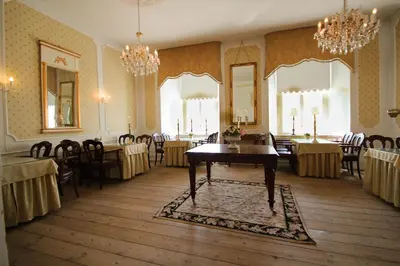 a dining room with tables and chairs and chandeliers at Kokkedal Slotshotel in Brovst
