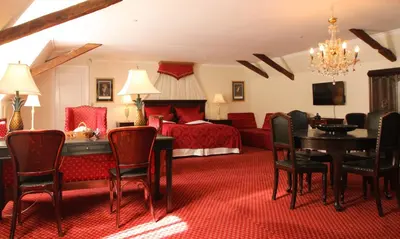 a hotel room with a bed and a table and chairs at Kokkedal Slotshotel in Brovst