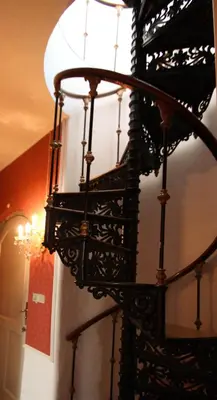 a black spiral staircase with a chandelier at Kokkedal Slotshotel in Brovst