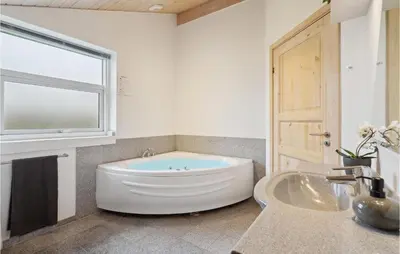 a bathroom with a tub and a sink and a window at Three-Bedroom Holiday Home In Vinderup in Vinderup