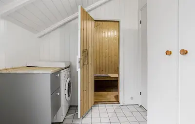 a laundry room with a washer and a wooden door at Three-Bedroom Holiday Home In Thyholm in Thyholm
