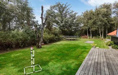 a yard with a wooden deck and a playground at Three-Bedroom Holiday Home In Thyholm in Thyholm