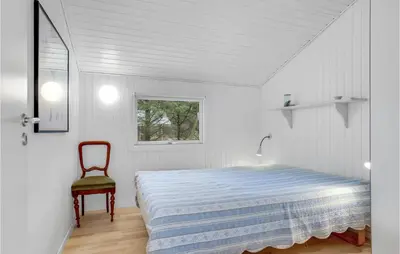 a white bedroom with a bed and a chair at Four-Bedroom Holiday Home In Fjerritslev in Fjerritslev