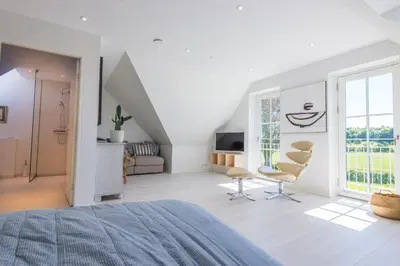 a white room with a bed and chairs in it at Kunstart20 in Saltum