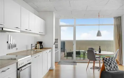 a kitchen with white cabinets and a table with a view at One-Bedroom Holiday Home In Ulfborg in Ulfborg