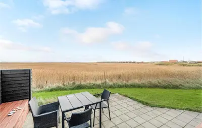 a patio with a table and chairs and a field at One-Bedroom Holiday Home In Ulfborg in Ulfborg