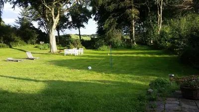a green yard with a bench in the grass at Slettegaard in Slettestrand
