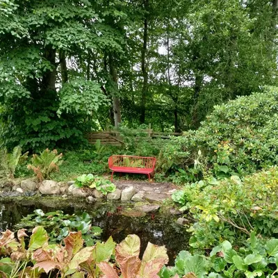 a red bench sitting in the middle of a garden at Slettegaard in Slettestrand