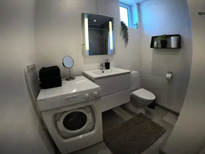 a bathroom with a washing machine and a sink at Thy Ferielejlighed in Thisted
