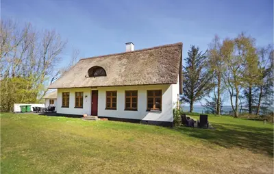 a white house with a roof on a grass field at Venøhus in Struer