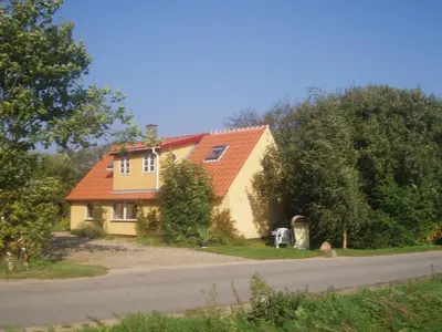 a yellow house with an orange roof on a road at Country house in Karby