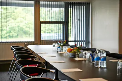 a long table with chairs in a room with windows at Motel Skive in Skive