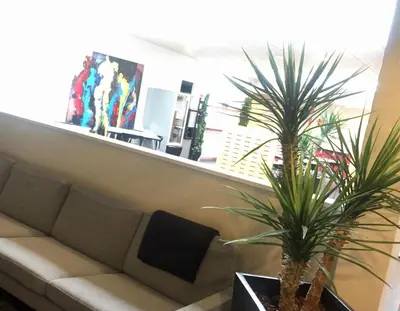 a living room with a couch and two palm trees at Motel Skive in Skive