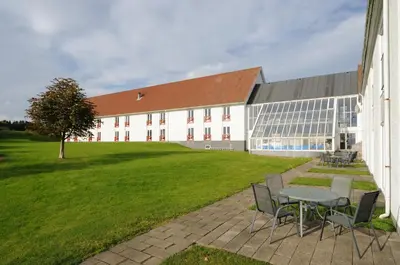 a building with a table and chairs in front of it at Hotel Limfjorden in Thisted