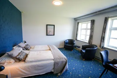a hotel room with a bed and two chairs at Hotel Søparken in Åbybro