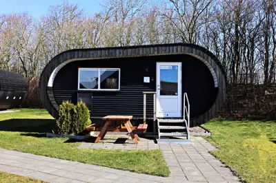 a black tiny house with a table and a door at Plexus Hytterne in Holstebro