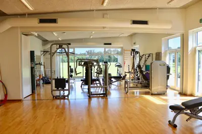a gym with several tread machines in a room with wood floors at Plexus Hytterne in Holstebro