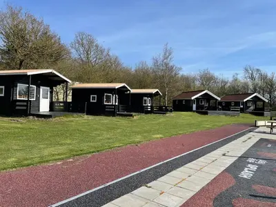 a row of black cabins in a park at Myrhoj Camping in Myrhøj