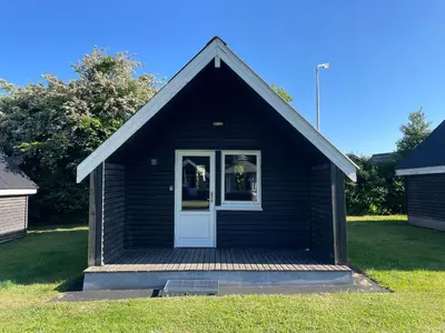 a small black house with a white door at Myrhoj Camping in Myrhøj