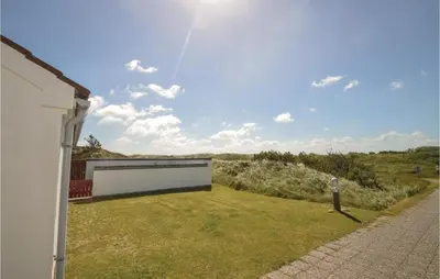 a white house with a grassy yard next to a building at Two-Bedroom Holiday Home In Pandrup in Pandrup