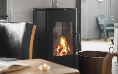 a black fireplace with a fire in it next to a table at Three-Bedroom Holiday Home In Pandrup in Pandrup