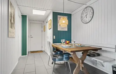 a dining room with a table and a clock on the wall at Three-Bedroom Holiday Home In Pandrup in Pandrup