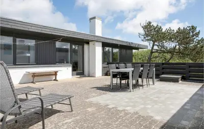 a patio with chairs and a table and a building at Three-Bedroom Holiday Home In Pandrup in Pandrup
